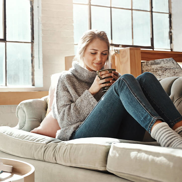 Frau sitzt mit Tee auf dem Sofa